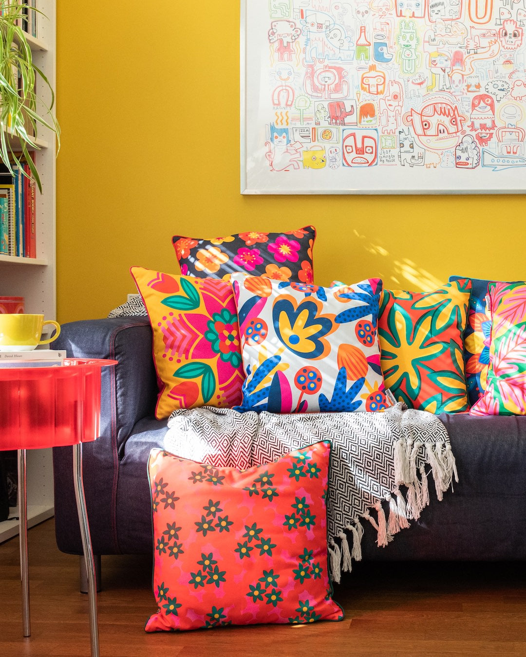 Bright, bold Republic of Happy patterned cushions styled on a sofa in a colourful, happy living room